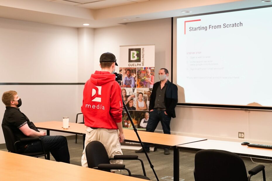 a man standing in front of a class room with a projector screen