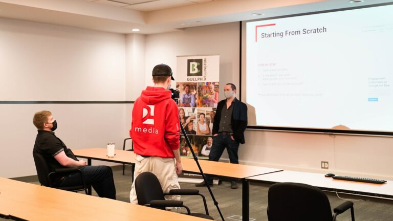 a man standing in front of a class room with a projector screen