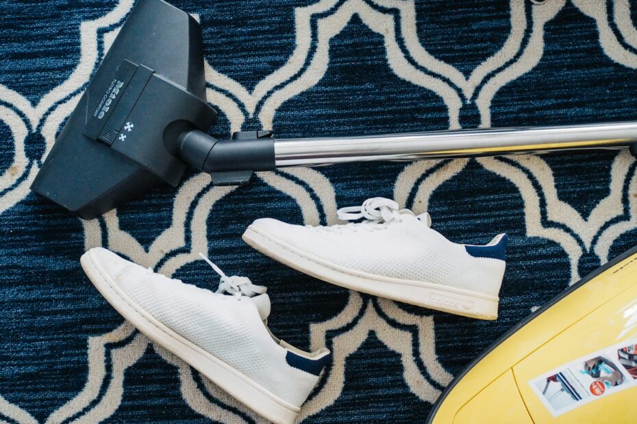 pair of white sneakers beside vacuum cleaner